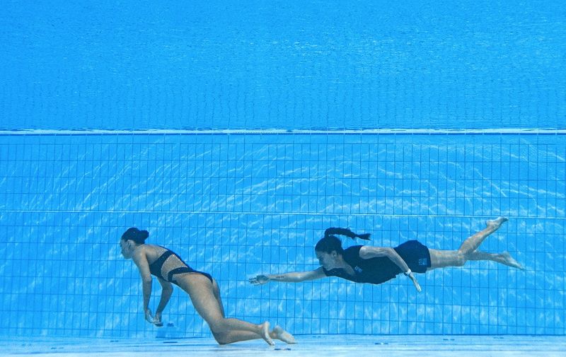 A member of Team USA (R) swims to recover USA's Anita Alvarez (L), from the bottom of the pool during an incendent in the women's solo free artistic swimming finals, during the Budapest 2022 World Aquatics Championships at the Alfred Hajos Swimming Complex in Budapest on June 22, 2022. (Photo by Oli SCARFF / AFP)