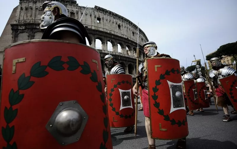 Men dressed up as ancient Roman soldiers walk by the Colosseum during a parade to celebrate the 2763rd anniversary of the legendary foundation of the city of Rome on April 18, 2010. The legend says that Rome was founded by twin brothers, Romulus and Remus on April 21 in 753BC. AFP PHOTO / Filippo MONTEFORTE / AFP / FILIPPO MONTEFORTE