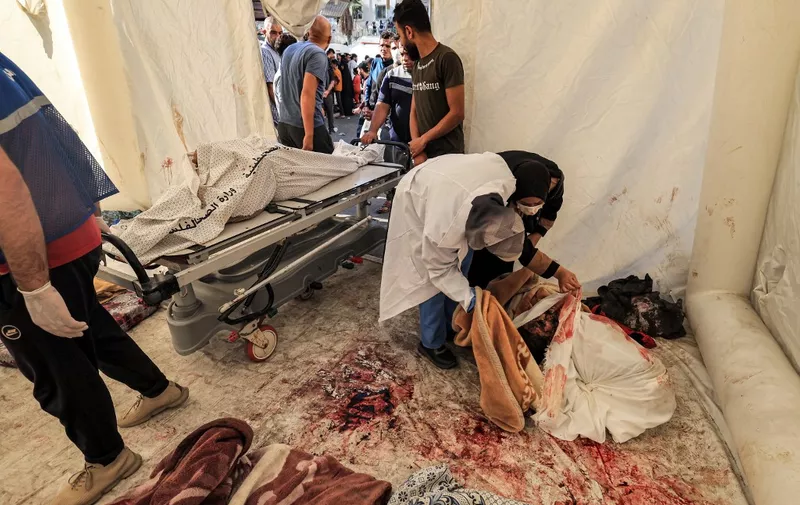 EDITORS NOTE: Graphic content / People inspect to identify one of the bodies of victims of the overnight strike at the Ahli Arab hospital at a makeshift tent at the site in central Gaza on October 18, 2023. A blast ripped through a hospital in war-torn Gaza killing hundreds of people late on October 17, sparking global condemnation and angry protests around the Muslim world. Israel and Palestinians traded blame for the incident, which an "outraged and deeply saddened" US President Joe Biden denounced while en route to the Middle East. (Photo by AFP)