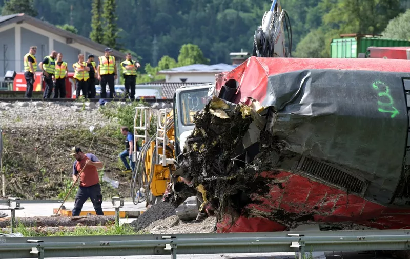 Police and workers are seen near an overturned railway carriage during salvage work at the site of a train derailment near Burgrain, north of Garmisch-Partenkirchen, southern Germany, on June 4, 2022, a day after the accident. - The death toll from the German train derailment near a Bavarian Alpine resort climbed to five on June 4 as a further body was recovered from the wreckage, police said. Investigators were combing the overturned carriages for victims and clues as to the cause of the accident on June 3 near Garmisch-Partenkirchen, a region gearing up to host the G7 summit in late June. (Photo by KERSTIN JOENSSON / AFP)