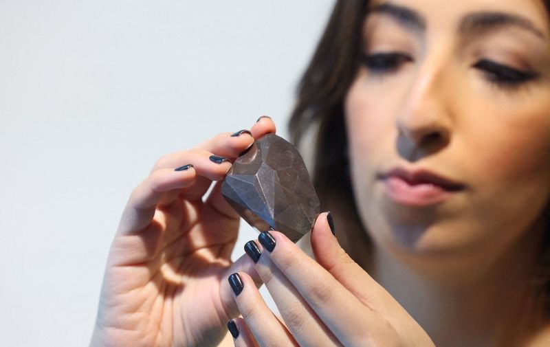 A picture taken on January 17, 2022 shows "The Enigma", a 555.55 carat black diamond, at Sotheby's in the Gulf emirate of Dubai. (Photo by Giuseppe CACACE / AFP)