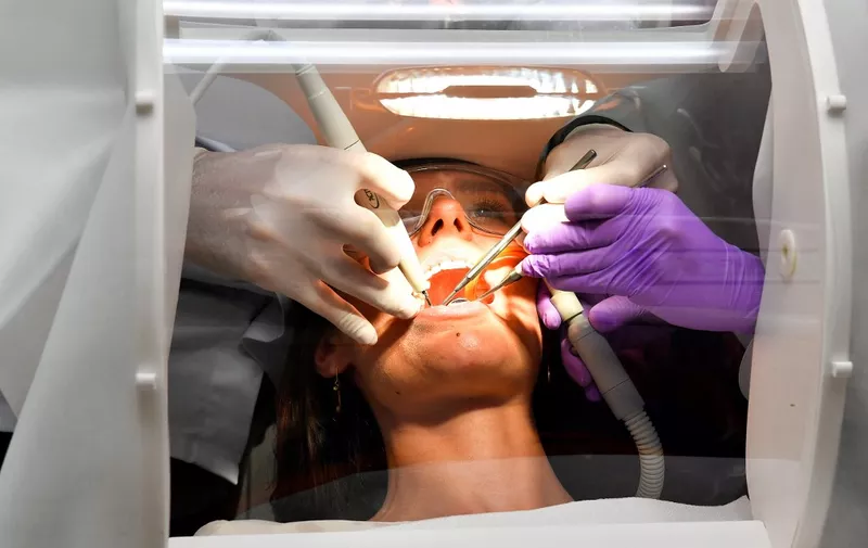 A patient receives care from a dentist protected by a plexiglass and silicon shield against the novel coronavirus (COVID-19), created by the Occisphere company, on July 7, 2020 in Toulouse, southern France. (Photo by GEORGES GOBET / AFP)