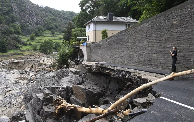 A policewoman takes a picture of a crater whera a road that has sunken in the city of  Altenahr, Rhineland-Palatinate, western Germany, on July 19, 2021, after devastating floods hit the region. - The German government on July 19, 2021 pledged to improve the country's under-fire warning systems as emergency services continued to search for victims of the worst flooding in living memory, with at least 165 people confirmed dead. (Photo by CHRISTOF STACHE / AFP)