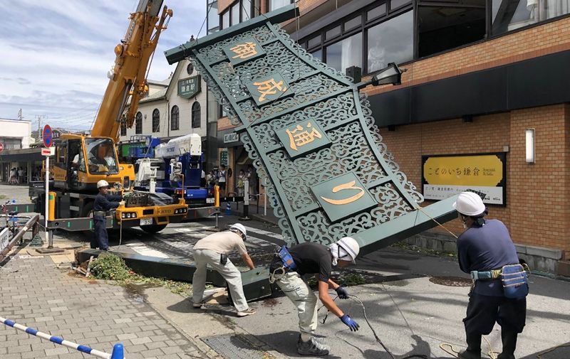 Workers remove a fallen signboard hit by typhoon Faxai in Kamakura, Kanagawa prefecture on September 9, 2019. - A powerful typhoon with potentially record winds and rain battered the Tokyo region on September 9, sparking evacuation warnings to tens of thousands, widespread blackouts and transport disruption. (Photo by jiji press / JIJI PRESS / AFP) / Japan OUT