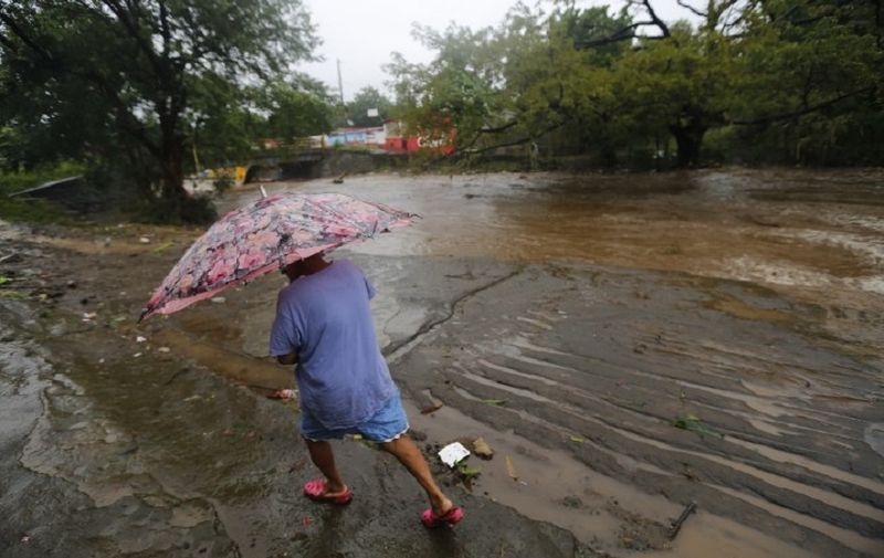 A woman walks in the rain near the flooded Masachapa River following the passage of Tropical Storm Nate in the city of Masachapa, about 60km from the city of Managua on October 5, 2017.
A tropical storm sliding north along Central America Thursday has unleashed heavy rains killing at least nine people in Costa Rica and Nicaragua, with forecasters predicting it could strengthen into a hurricane headed for the United States. / AFP PHOTO / INTI OCON