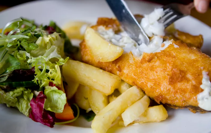 A big, mouth watering plate of fish and chips with side salad and tartar sauce.