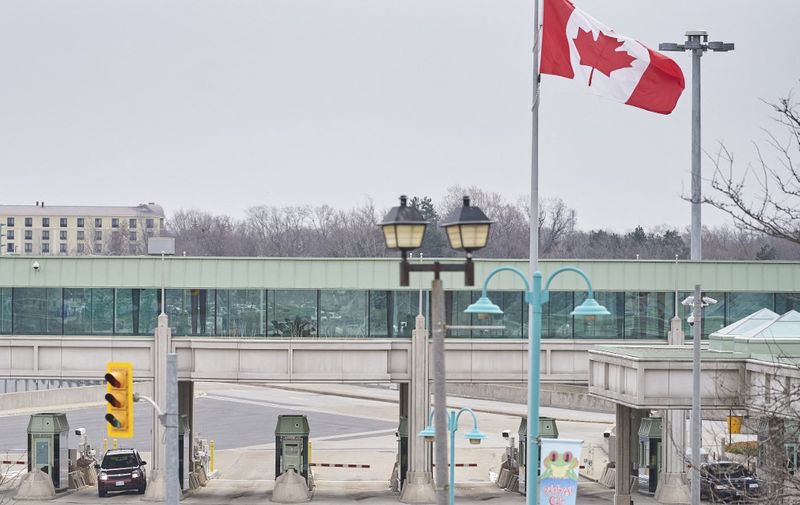 A car stops at a Canadian Customs booth in Niagara Falls, Ontario, on March 18, 2020, hours after Prime Minister Justin Trudeau announced the closing of the border with the US to all tourists. - US and Canada have mutually agreed on March 18, 2020 to temporarily restrict " non essential traffic" accross Canada-US border due to the coronavirus pandemic. (Photo by Geoff Robins / AFP)