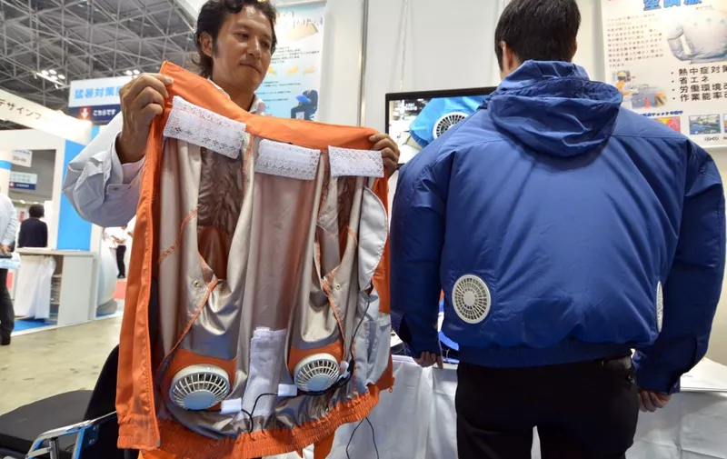Toru Ichigaya (L), an employee of Japanese power-saving goods venture "Kuchofuku", displays an air-conditioned jacket which has cooling fans on its back, at the Heat Solutions exhibition in Tokyo on July 23, 2015. Temperatures climbed over 35 degree Celsius in the Tokyo metropolitan area following the conclusion of the rainy season. AFP PHOTO / Yoshikazu TSUNO (Photo by YOSHIKAZU TSUNO / AFP)