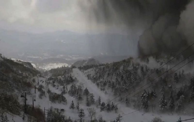 This handout image taken from the Kusatsu Mt. Shirane Gondola Unjo Camera and released by the Kusatsu Town Office on January 23, 2018 shows thick black smoke sliding down the snow-covered side of the volcano towards a ski slope after an eruption.
A Japanese soldier was killed on January 23 after a volcano erupted near the popular Japanese ski resort, sparking an avalanche that left several injured and scores stranded up a mountain, officials said. / AFP PHOTO / KUSATSU TOWN OFFICE / Handout / -----EDITORS NOTE --- RESTRICTED TO EDITORIAL USE - MANDATORY CREDIT "AFP PHOTO / KUSATSU TOWN OFFICE" - NO MARKETING - NO ADVERTISING CAMPAIGNS - DISTRIBUTED AS A SERVICE TO CLIENTS