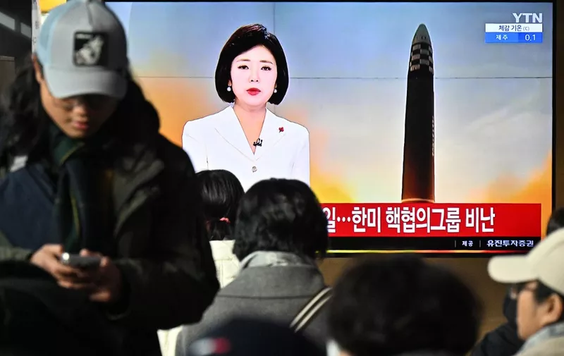 People sit near a television screen showing a news broadcast with file footage of a North Korean missile test, at a railway station in Seoul on December 18, 2023. North Korea fired another internationally banned "long-range ballistic missile" on December 18, the South's military said, after Pyongyang voiced outrage over deeper nuclear cooperation between Seoul and Washington. (Photo by Anthony WALLACE / AFP)
