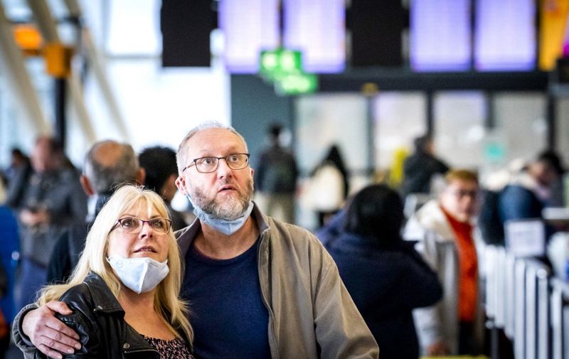 Travellers wearing facemasks for protective measures, look at the information board in the hall of the Schiphol Airport, in the outskirts of Amsterdam, on March 18, 2020 as several airlines cancel their flights related to the Covid-19 outbreak hitting Europe. - Since the virus first emerged in late December, 8,091 people have died around the world, out of more than 199,470 cases according to an AFP tally based on official sources at 1100 GMT on March 18, 2020 (Photo by Remko DE WAAL / ANP / AFP) / Netherlands OUT