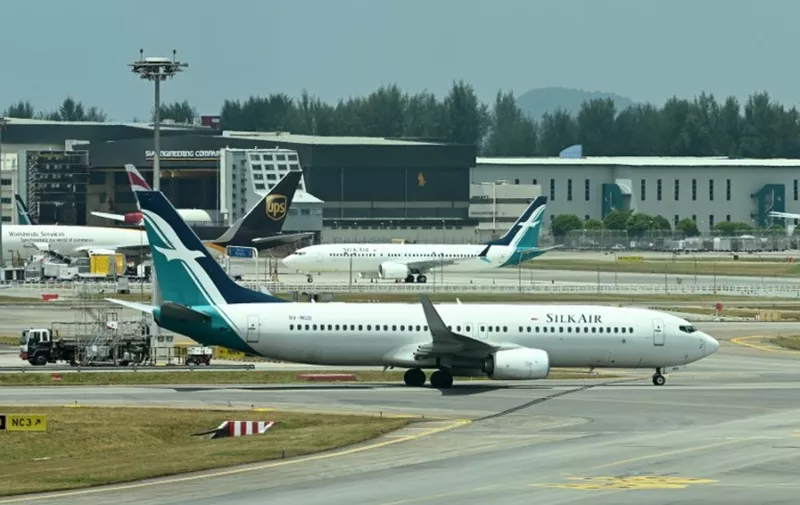 A SilkAir Boeing 737 MAX aircraft (background C) is parked on the tarmac of Changi International Airport in Singapore on March 12, 2019 while a SilkAir Boeing 737-8SA (front) taxi on a runway. - Singapore's aviation regulator on March 12, banned the use of Boeing 737 MAX aircraft in the country's airspace following a deadly Ethiopia plane crash at the weekend. (Photo by Roslan RAHMAN / AFP)