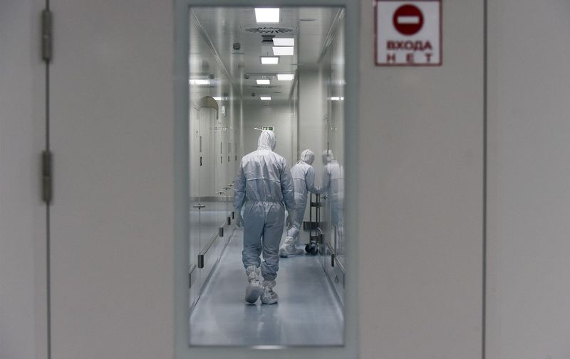 Employees wearing protective equipment walk in a passage at the headquarters of Russia's biotech company BIOCAD, which is developing its own vaccine against the new coronavirus and working on another one in cooperation with the country's virus research centre in Siberia, Vektor, in Strelna on May 20, 2020. (Photo by OLGA MALTSEVA / AFP)