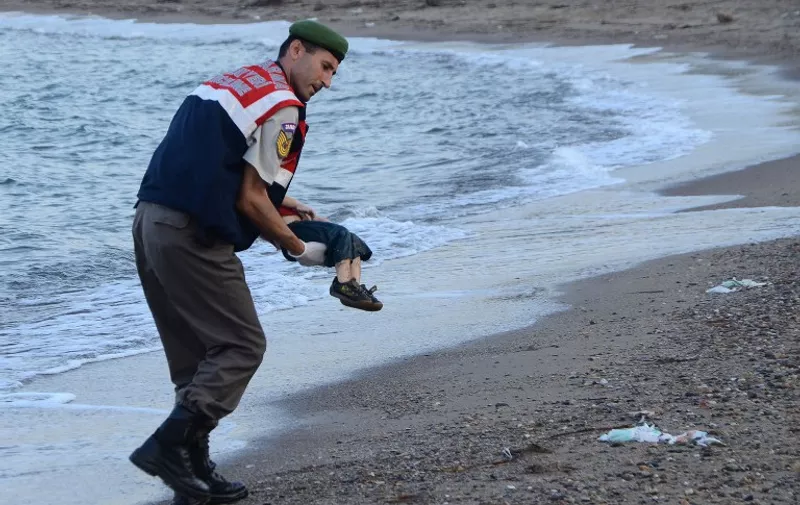 GRAPHIC CONTENT
A Turkish police officer carries a migrant child's dead body off the shores in Bodrum, southern Turkey, on September 2, 2015 after a boat carrying refugees sank while reaching the Greek island of Kos. Thousands of refugees and migrants arrived in Athens on September 2, as Greek ministers held talks on the crisis, with Europe struggling to cope with the huge influx fleeing war and repression in the Middle East and Africa. AFP PHOTO / DOGAN NEWS AGENCY
= TURKEY OUT =