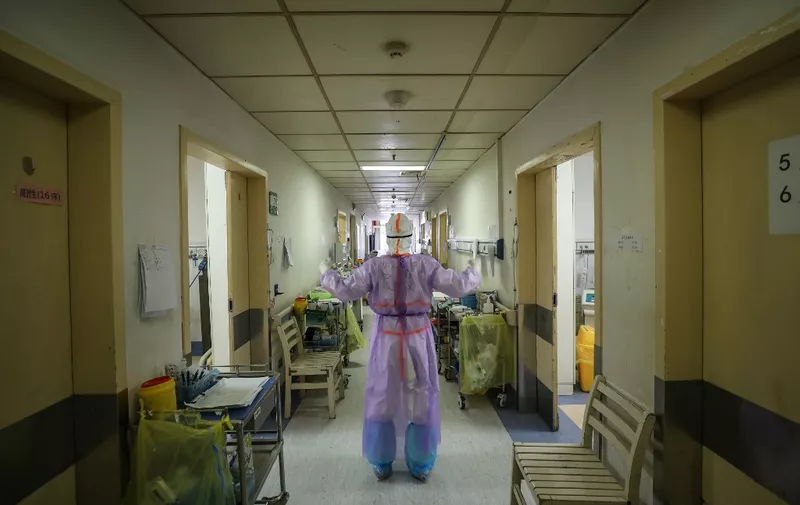 This photo taken on February 28, 2020 shows a medical staff member doing stretch at the Red Cross hospital in Wuhan in China's central Hubei province. - China on March 1 reported 35 more deaths from the new coronavirus, taking the toll in the country to 2,870. (Photo by STR / AFP) / China OUT