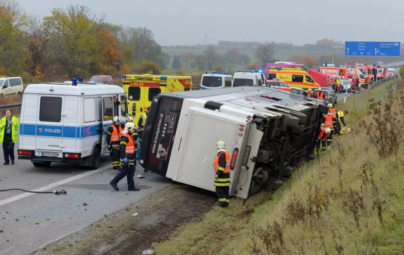 Rescue workers and policemen are seen at the site of a bus accident on the A4 highway near Erfurt, eastern Germany, on October 30, 2015. According to the police, a five-year old boy was killed in the accident and at least five other children were severely injured when the bus fell down a slope after an overtaking manoeuvre.          AFP PHOTO / MARCUS SCHEIDEL