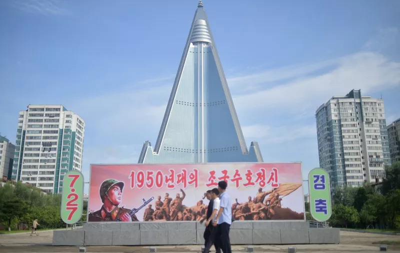 Pedestrians walk past the Ryugyong Hotel in Pyongyang on July 27, 2023, on the 70th anniversary of the end of the Korean War, which the country celebrates as the day of "Victory in the Fatherland Liberation War. (Photo by KIM Won Jin / AFP)
