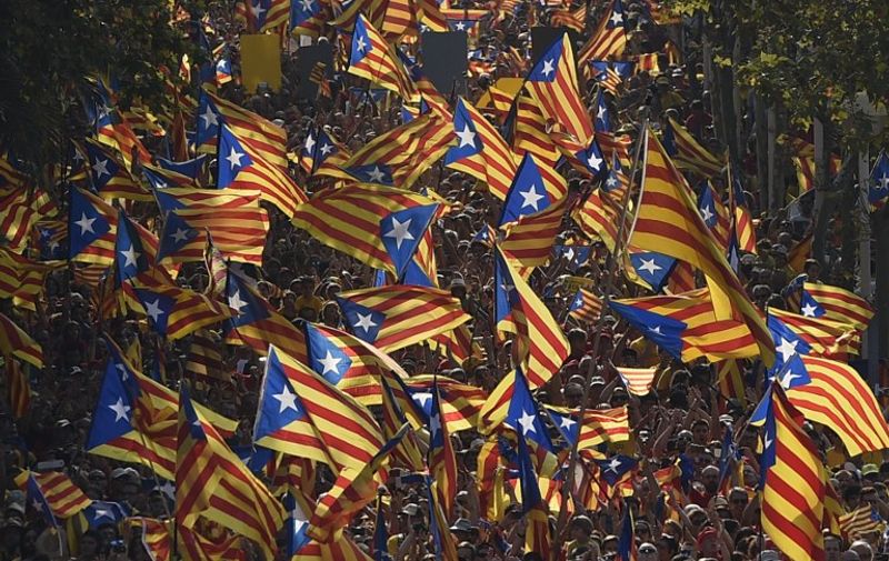 Catalan hold Catalan independentist flags (Estelada) during celebrations of Catalonia National Day (Diada) in Barcelona on September 11, 2014. Red and yellow flags filled the streets of Barcelona today as Catalan nationalists fired up by Scotland's independence referendum rallied to demand a vote on breaking away from Spain. Demonstrators planned to mass in the late afternoon along two central Barcelona avenues in the shape of a giant letter "V" for vote.    AFP PHOTO/ LLUIS GENE