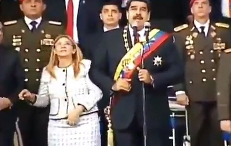 Screengrab taken from a handout video released by Venezuelan Television (VTV) showing Venezuelan President Nicolas Maduro (C), his wife Cilia Flores (L) and military authorities reacting to a loud band during a ceremony to celebrate the 81st anniversary of the National Guard in Caracas on August 4, 2018.
Maduro was unharmed after an exploding drone "attack", the minister of communication Jorge Rodriguez said following the incident, which saw uniformed military members break ranks and scatter after a loud bang interrupted the leader's remarks and caused him to look to the sky, according to images broadcast on state television. / AFP PHOTO / VENEZUELAN TELEVISION (VTV) / HO / RESTRICTED TO EDITORIAL USE - MANDATORY CREDIT "AFP PHOTO / VENEZUELAN TELEVISION - VTV" - NO MARKETING NO ADVERTISING CAMPAIGNS - DISTRIBUTED AS A SERVICE TO CLIENTS