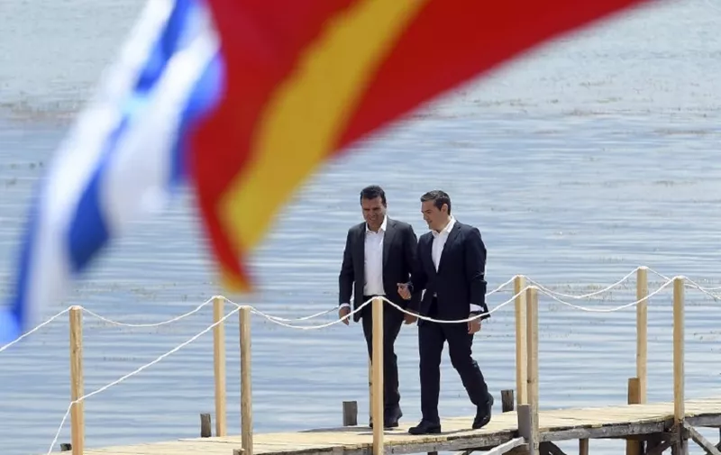 Macedonian Prime Minister Zoran Zaev (L) welcomes Greek Prime Minister Alexis Tsipras on the shore of the Lake Prespa near Otesevo on June 17, 2018. 
The foreign ministers of Greece and Macedonia signed a historic preliminary accord to end a 27-year bilateral row by renaming Macedonia to Republic of North Macedonia.   / AFP PHOTO / Maja ZLATEVSKA / ALTERNATIVE CROP