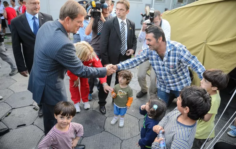 Slovenian Prime Minister Miro Cerar (2nd L) shakes hands with a migrant at a registration center in Brezice on September 19, 2015. Hundreds of migrants gathered on Croatia's main border crossings with Slovenia today, seeking transit through Slovenian territory in their bid to travel to northern Europe, AFP reporters and local media said.  AFP PHOTO / JURE MAKOVEC