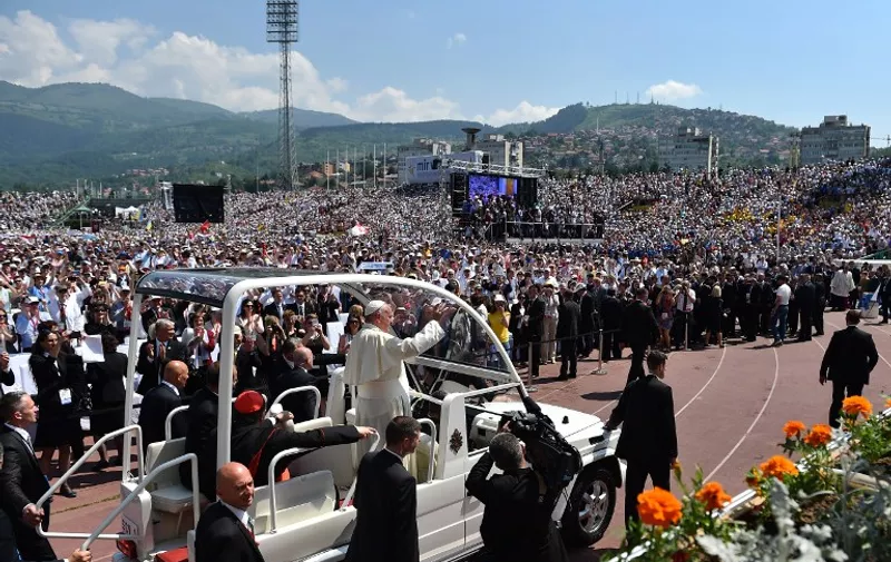 Pope Francis greets the crowd from the popemobile as he arrives to celebrate a mass at the Sarajevo's city stadium as part of a one day visit in Bosnia, on June 6, 2015 in Sarajevo. Pope Francis arrived in Sarajevo for a visit aimed at bolstering reconciliation between war-scarred Bosnia's Serb, Croat and Muslim communities. The trip comes 20 years after the end of a 1992-95 conflict that ripped the Balkan state apart and left it permanently divided along ethnic lines. AFP PHOTO  / GABRIEL BOUYS