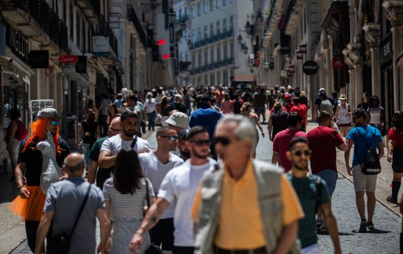 People walk down Rua do Carmo street in downtown Lisbon on May 28, 2022. (Photo by CARLOS COSTA / AFP)