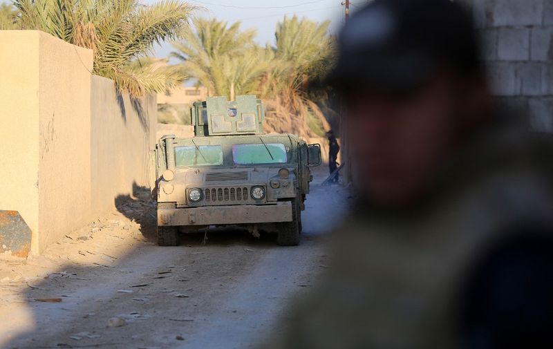 Iraqi troops and allied paramilitaries advance on December 6, 2015 down a street in Husayba, an Iraqi rural town in the Euphrates Valley seven kilometres (4.5 miles) east of Ramadi, where government forces have been closing on Islamic State (IS) group militants who seized the Anbar province's capital in May after a three-day blitz involving dozens of huge truck bombs. Iraqi security forces have fought their way to the outskirts of Ramadi, where they have been battling the IS jihadists in the past weeks. AFP PHOTO / AHMAD AL-RUBAYE (Photo by AHMAD AL-RUBAYE / AFP)