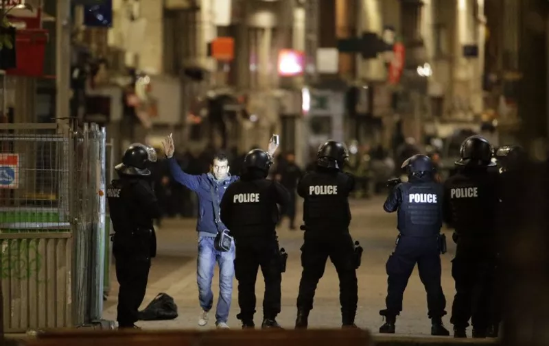 A passerby raises his arms in front of Police forces in the northern Paris suburb of Saint-Denis city center, on November 18, 2015, as Police special forces raid an appartment, hunting those behind the attacks that claimed 129 lives in the French capital five days ago. At least one person was killed in an apartment targeted in the operation aimed at the suspected mastermind of the attacks, Belgian Abdelhamid Abaaoud, and police had been wounded in the shootout. AFP PHOTO / KENZO TRIBOUILLARD / AFP / KENZO TRIBOUILLARD