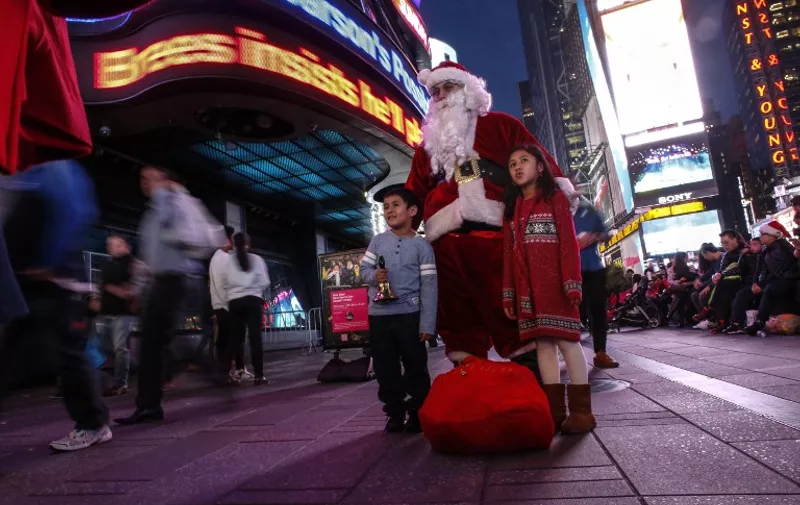 NEW YORK, NY - DECEMBER 24: A man dressed as Santa Claus greets people in Times Square on December 24, 2015 in New York City. Last-minute shoppers get some of the best deals, many of the major retailers, including Macy's and Kohl's, are set to stay open until 6 p.m. this Christmas Eve.   Kena Betancur/Getty Images/AFP