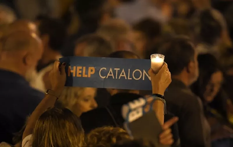 A woman holds a candle and a placard reading "Help Catalonia" during candle-lit demonstration in Barcelona against the arrest of two Catalan separatist leaders on October 17, 2017.
Catalonia braced for protests after a judge ordered the detention of two powerful separatist leaders, further inflaming tensions in the crisis over the Spanish region's chaotic independence referendum. / AFP PHOTO / LLUIS GENE