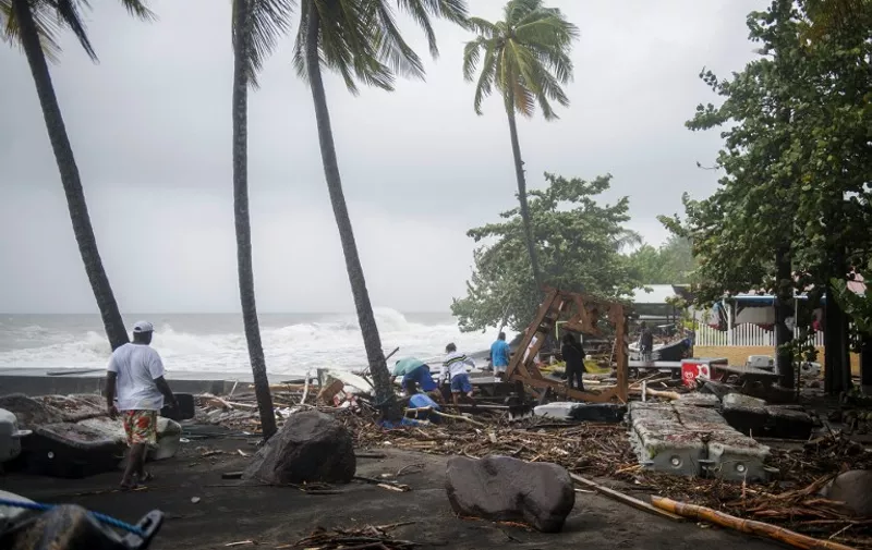 People walk among debris at a restaurant in Le Carbet, on the French Caribbean island of Martinique, after it was hit by Hurricane Maria, on September 19, 2017.
Hurricane Maria smashed into the eastern Caribbean island of Dominica on September 19, with its prime minister describing devastating damage as winds and rain from the storm also hit territories still reeling from Irma. Martinique, a French island south of Dominica, suffered power outages but avoided major damage. / AFP PHOTO / Lionel CHAMOISEAU