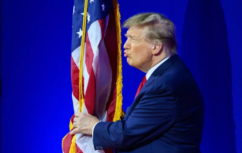 Former US president and 2024 presidential hopeful Donald Trump kisses the US flag as he arrives to speak during the annual Conservative Political Action Conference (CPAC) meeting on February 24, 2024, in National Harbor, Maryland. (Photo by Mandel NGAN / AFP)
