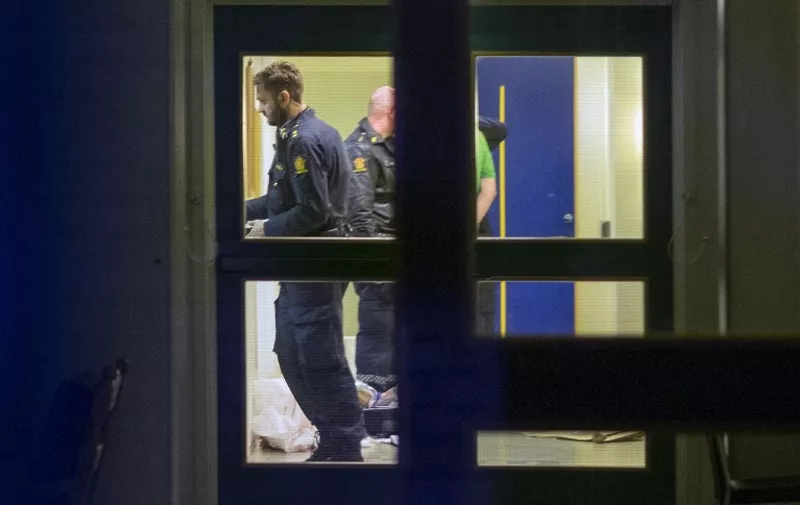 Police have arrested a suspect (partly hidden R) after two police officers were stabbed in Vennesla, some 350 km south west of Oslo on November 20, 2015. Norwegian police said they had arrested a man suspected of stabbing two police officers and seriously wounding them in the town of Vennesla. The motive for the attack was not immediately known. AFP PHOTO / NTB SCANPIX / TOR ERIK SCHRODER   +++   NORWAY OUT +++ / AFP / NTB SCANPIX / Tor Erik Schroder