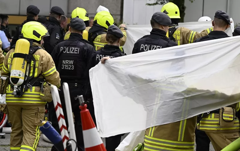 Shielded by paramedics, an injured person is brought to an ambulance close to the site of an explosion on May 11, 2023 in Ratingen, western Germany. Several people were injured, among them three policemen and several firefighters, in the detonation that occured in a flat of a high rise building, according to the police. The cause of the explosion is still not clear. (Photo by Roberto Pfeil / AFP)