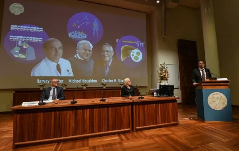 Thomas Perlmann (R), the Secretary of the Nobel Committee, speaks to announce the winners of the 2020 Nobel Prize in Physiology or Medicine (On screen L-R) American Harvey Alter, Briton Michael Houghton and American Charles Rice, as Nobel Committee members Patrik Ernfors (L) and Gunilla Karlsson Hedestam look on, during a press conference at the Karolinska Institute in Stockholm, Sweden, on October 5, 2020. - Americans Harvey Alter and Charles Rice as well as Briton Michael Houghton win the 2020 Nobel Medicine Prize for the discovery of Hepatitis C virus. (Photo by Jonathan NACKSTRAND / AFP)