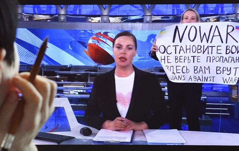 A woman looks at a computer screen watching a dissenting Russian Channel One employee entering Ostankino on-air TV studio during Russia's most-watched evening news broadcast, holding up a poster which reads as "No War" and condemning Moscow's military action in Ukraine in Moscow on March 15, 2022. - As a news anchor Yekaterina Andreyeva launched into an item about relations with Belarus, Marina Ovsyannikova, who wore a dark formal suit, burst into view, holding up a hand-written poster saying "No War" in English. (Photo by AFP)