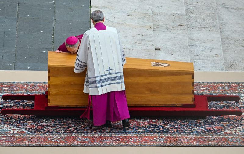 German Archbishop Georg Gaenswein (L) kisses the coffin of Pope Emeritus Benedict XVI at the start of his funeral mass at St. Peter's square in the Vatican, on January 5, 2023. - Pope Francis will preside on January 5 over the funeral of his predecessor Benedict XVI at the Vatican, an unprecedented event in modern times expected to draw tens of thousands of people. (Photo by Filippo MONTEFORTE / AFP)