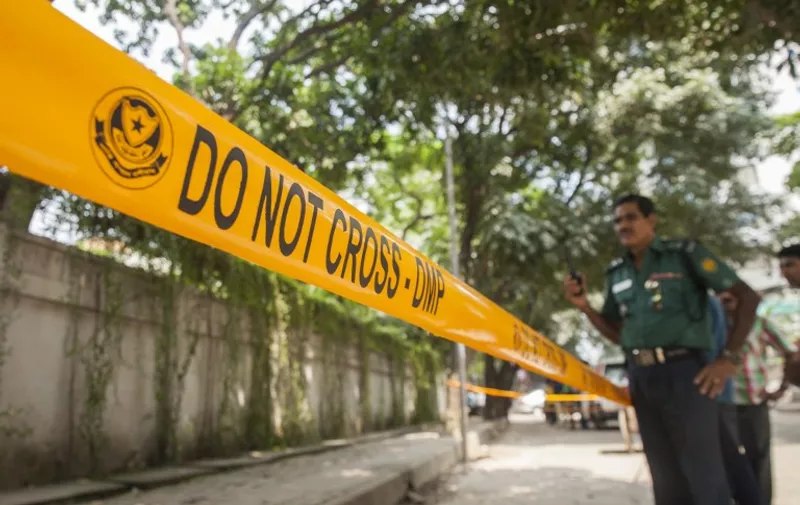 Bangladeshi police officers stand guard at the site where an Italian charity worker was shot to death by attackers in Dhaka on September 29, 2015. International schools closed down in Bangladesh on September 29 and Western embassies restricted their diplomats' movements after an Italian aid worker was shot dead in an attack claimed by the Islamic State group. Home Minister Asaduzzaman Khan sought to calm escalating security fears in the country, denying the jihadist group was behind the murder on september 28 and describing it as an "isolated incident". AFP PHOTO / STR / AFP PHOTO / STRINGER