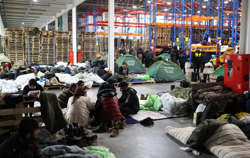 Migrants stay in the transport and logistics centre near the Bruzgi border point on the Belarusian-Polish border in the Grodno region on November 22, 2021. Belarusian leader Alexander Lukashenko said November 22 that the European Union was refusing to discuss the fate of 2,000 migrants wishing to go to Europe and stranded in Belarus. (Photo by Andrei POKUMEIKO / BELTA / AFP) / Belarus OUT
