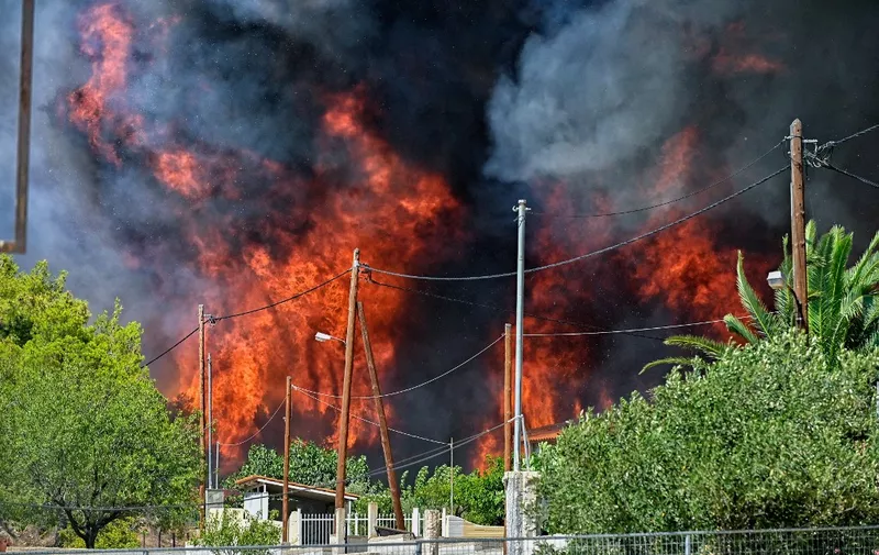 Wildfire rages by the houses in the settlement of Irini, near the resort town of Loutraki, some 80 kilometres east of Athens, on July 17, 2023. Greek police on July 17, 2023 arrested a man suspected of starting an ongoing wildfire near Athens fuelled by a heatwave and strong winds, firefighters said.
"Police carried out the arrest of a foreigner who allegedly caused the fire" in Kouvaras, around 50 kilometres (30 miles) southeast of Athens, said fire service spokesman Yannis Artopios. (Photo by Valerie GACHE / AFP)