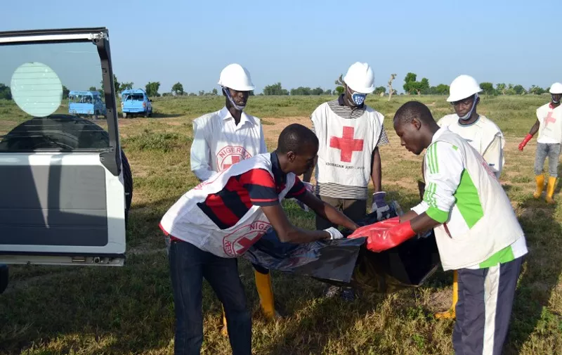 Officials of Red Cross try to remove a dead body at the scene of the blast in Miduguri on October 16, 2015. At least 34 people were killed in a wave of suicide bomb attacks in northeast Nigeria, as the military warned Boko Haram militants threaten the country's sovereignty. Thirty died in a double bombing on a mosque in Molai on Thursday night. AFP PHOTO / STRINGER / AFP / STRINGER