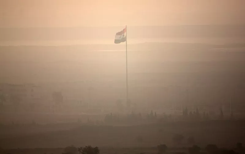 A picture taken from the Israeli-annexed Golan Heights shows a Syrian flag hoisted on a flagpole moments before its was removed during fighting between forces loyal to Syrian President Bashar Assad and rebel fighters, near the Quneitra border crossing on September 1, 2014. Heavy fighting between Syrian government troops and opposition forces overflowed into the buffer zone separating Syrian and Israeli-occupied territory over the weekend. AFP PHOTO/ MENAHEM KAHANA / AFP PHOTO / MENAHEM KAHANA