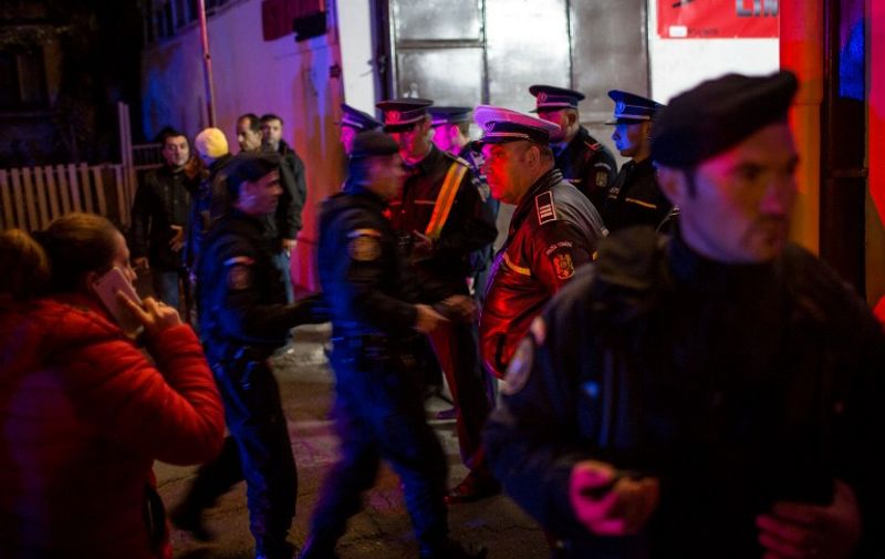 Emergency service and police forces gather near a club in Bucharest October 31, 2015, after an explosion. More than 20 people died and dozens were injured in an explosion followed by a fire, which took place Friday evening at a club during a music concert , where at that time there were hundreds people. Romanian Interior Minister, Gabriel Oprea announced that there are at least 26 dead. AFP PHOTO ANDREI PUNGOVSCHI