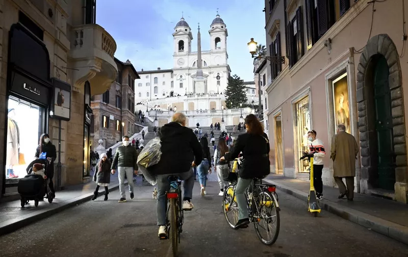 People cycle across the Via dei Condotti luxury shopping street towards Piazza di Spagna and the Spanish steps in downtown Rome on March 13, 2021 before the government tightens restrictions across most of the country from March 15, facing a "new wave" after it recorded almost 26,000 new Covid-19 cases and another 373 deaths on March 11. (Photo by Alberto PIZZOLI / AFP)