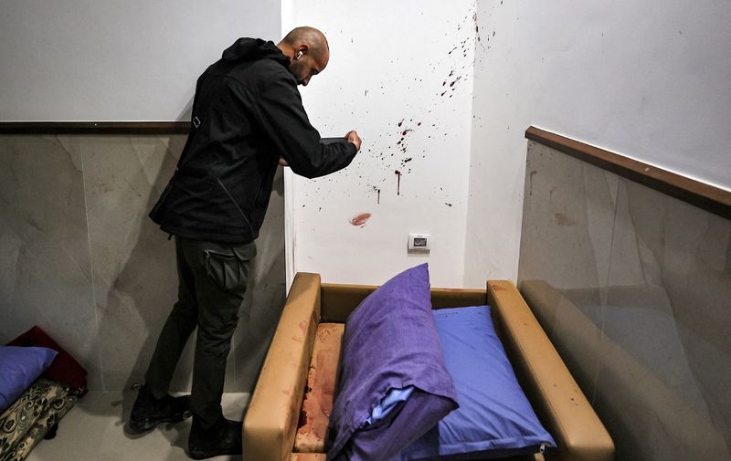 EDITORS NOTE: Graphic content / A man checks blood splatters on a wall at the Ibn Sina hospital in Jenin in the occupied West Bank on January 30, 2024. Israeli forces shot dead three Palestinians at the hospital early on January 30, the Palestinian health ministry said, while the army said the three belonged to a Hamas "terrorist cell". (Photo by Zain JAAFAR / AFP)