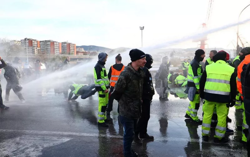 Police use water cannon and tear gas to disperse the dockers blocking gate 4 while demonstrating against the Green Pass in the port of Trieste following a three-day demonstration against a new mandatory workplace Covid-19 pass, on October 18, 2021. - The police cannons target hundreds of remaining protestors and port workers who have been blocking one of the port entrances since October 15, to protest against Italy's so-called Green Pass. (Photo by STRINGER / ANSA / AFP) / Italy OUT