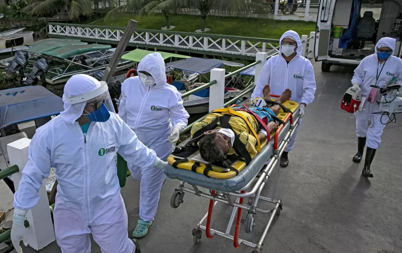 Health personnel of a medical emergency response service carry Brazilian Eladio Lopes, 79, -infected with the new coronavirus- on a stretcher to be transferred on an ambulance boat from the community of Portel to a hospital in Breves, on Marajo island, Para state, Brazil, on May 25, 2020. - Ambulance boat services allow critical COVID-19 patients to be tranferred in very remote areas surrounded by water in Brazil. (Photo by TARSO SARRAF / AFP)