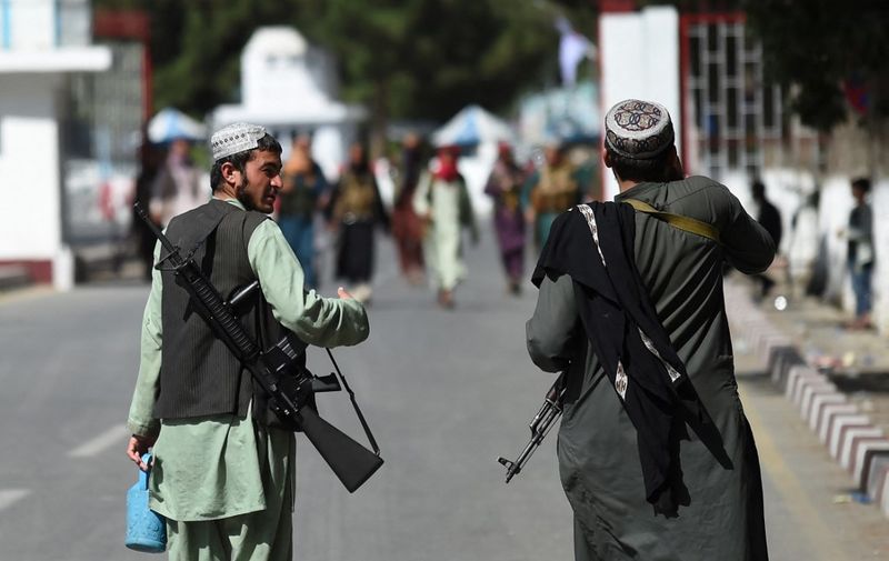 Taliban fighters walk at the main entrance gate of Kabul airport in Kabul on August 28, 2021, following the Taliban stunning military takeover of Afghanistan. (Photo by WAKIL KOHSAR / AFP)