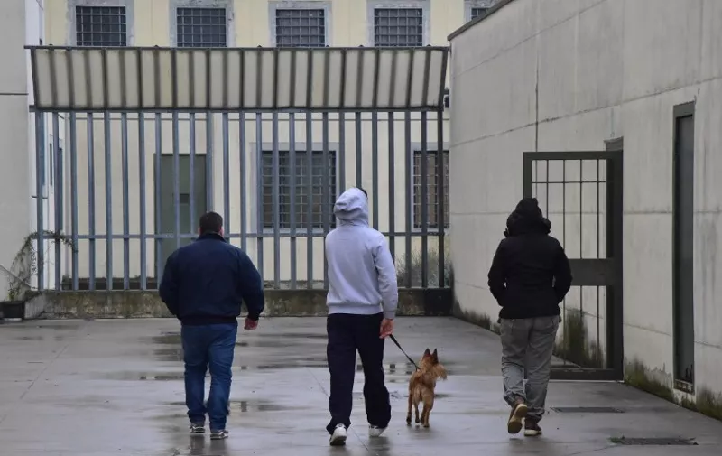An inmate (C) walks with a dog as part of the "pet therapy project" at the Bollate penitentiary near Milan, on November 26, 2014.  AFP PHOTO / GIUSEPPE CACACE / AFP PHOTO / GIUSEPPE CACACE